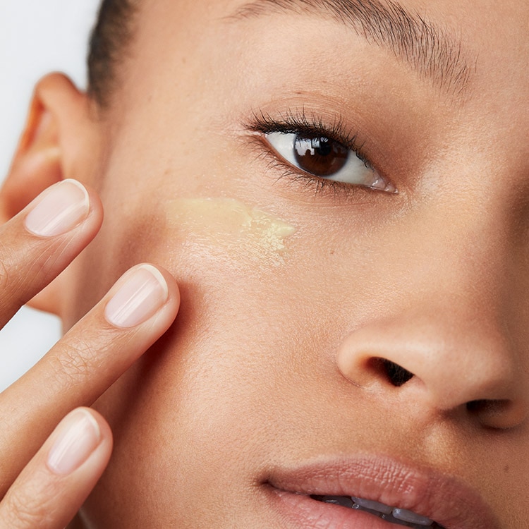 Close up of Vitamin Enriched Face Base with swatch behind over a pale blue background